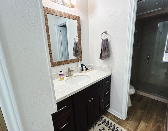 bathroom featuring vanity, a shower with shower door, and toilet