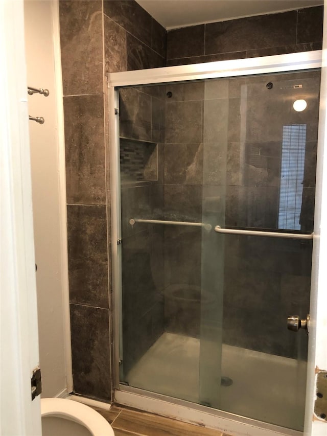 bathroom featuring a shower with shower door and toilet