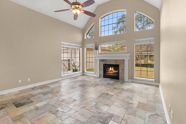 unfurnished living room featuring a tiled fireplace, ceiling fan, crown molding, and high vaulted ceiling