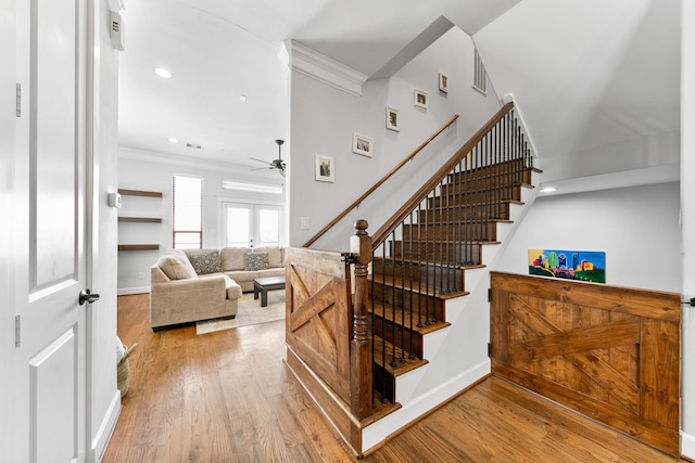 stairs featuring ornamental molding, wood-type flooring, ceiling fan, and french doors