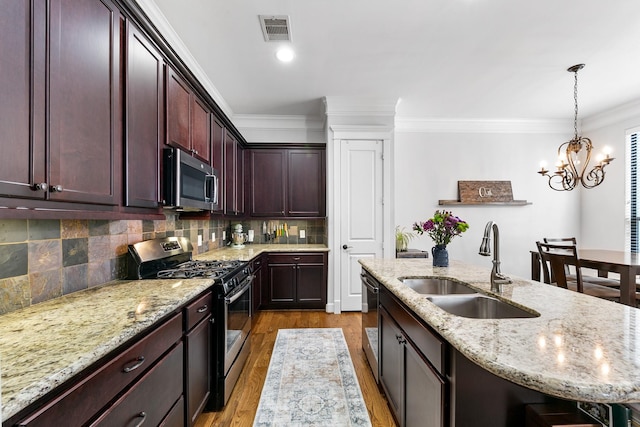 kitchen with sink, a kitchen island with sink, light stone counters, stainless steel appliances, and crown molding