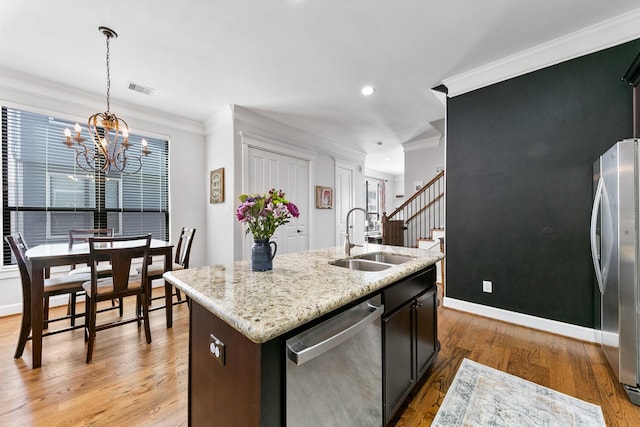 kitchen with sink, crown molding, stainless steel appliances, an island with sink, and decorative light fixtures