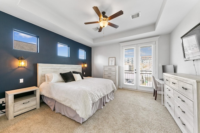 carpeted bedroom with ceiling fan, access to exterior, a raised ceiling, and multiple windows