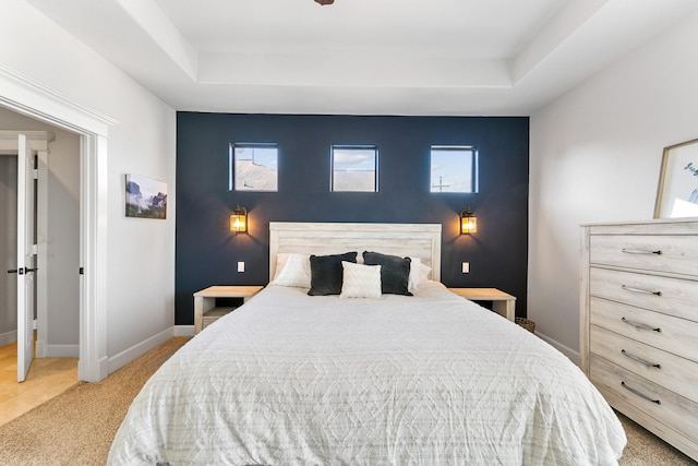 bedroom featuring light carpet, multiple windows, and a raised ceiling