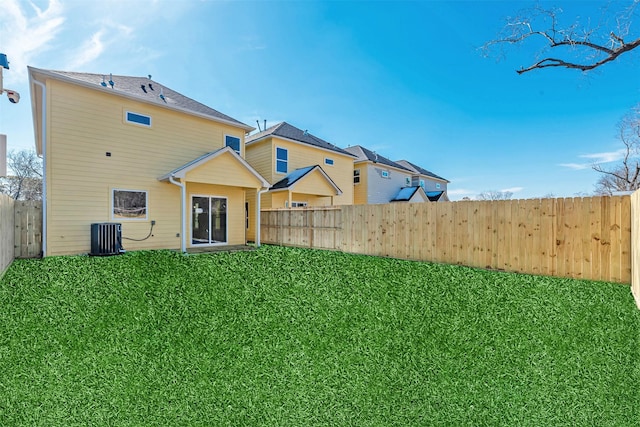 back of house featuring central AC unit and a lawn