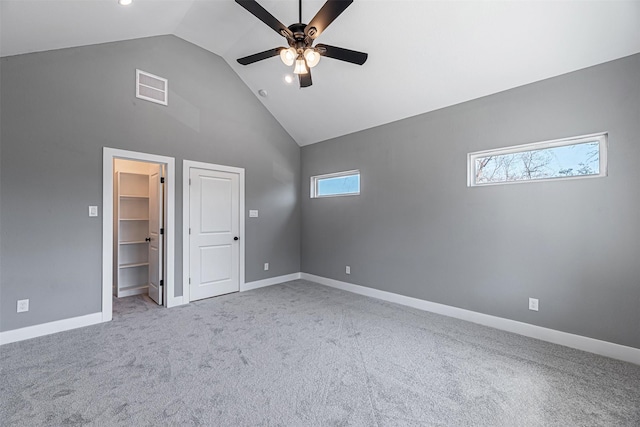 unfurnished bedroom featuring ceiling fan, high vaulted ceiling, a spacious closet, light colored carpet, and a closet