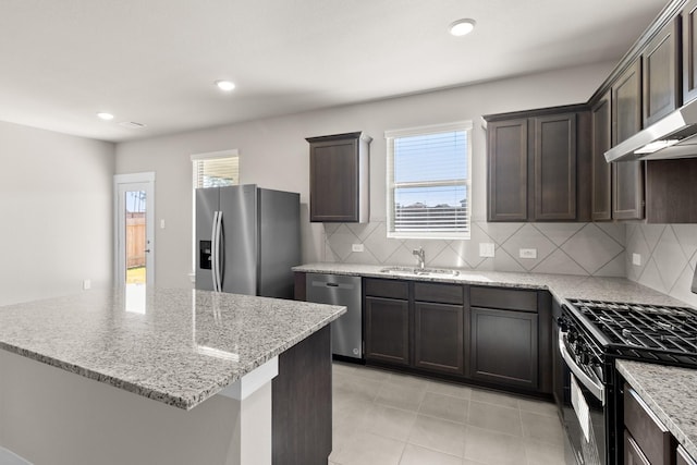 kitchen with tasteful backsplash, appliances with stainless steel finishes, light stone countertops, and sink