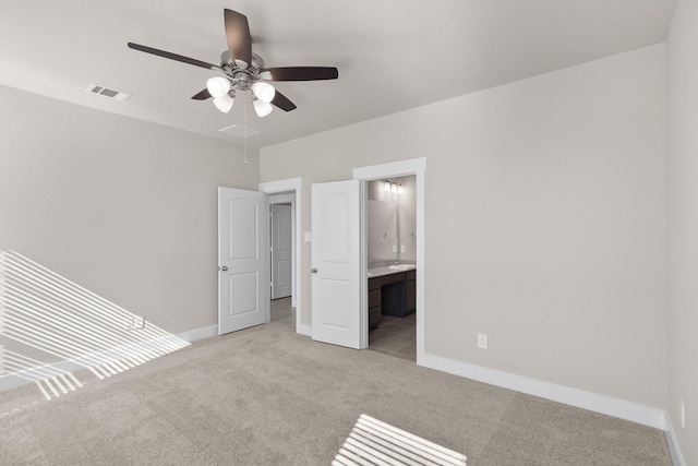 unfurnished bedroom featuring ceiling fan, light colored carpet, and ensuite bath