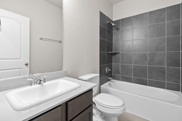 full bathroom featuring tiled shower / bath, vanity, and toilet