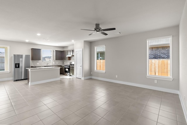 unfurnished living room featuring light tile patterned floors, baseboards, and ceiling fan