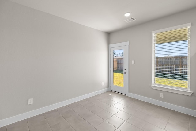 empty room featuring baseboards, visible vents, and plenty of natural light
