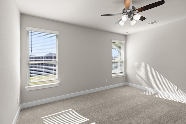 carpeted spare room featuring visible vents, baseboards, and ceiling fan