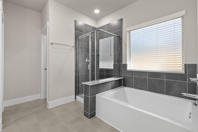 bathroom with tile patterned floors, a garden tub, baseboards, and a stall shower