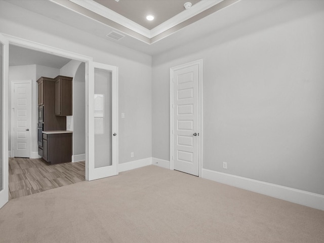 unfurnished room with french doors, crown molding, light carpet, and a tray ceiling