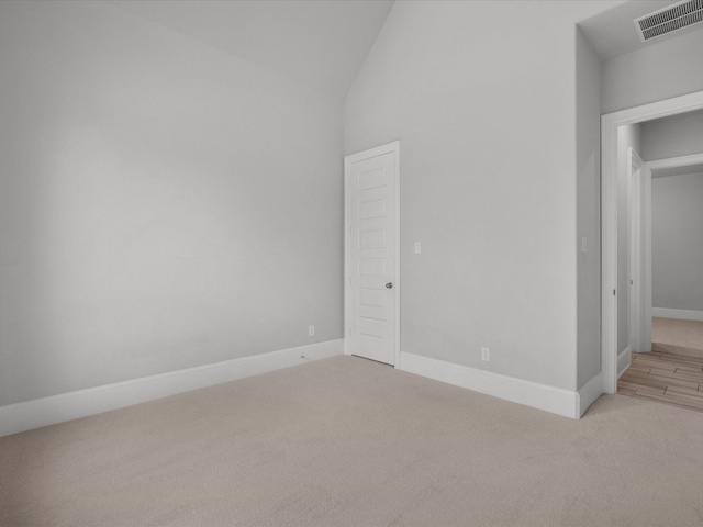 carpeted spare room featuring high vaulted ceiling