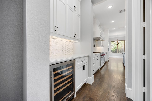 bar featuring tasteful backsplash, white cabinetry, high end range, custom range hood, and beverage cooler