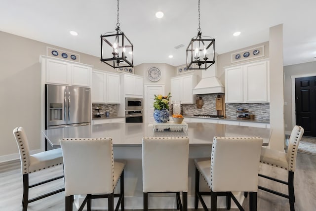 kitchen with stainless steel appliances, a large island, white cabinets, and light hardwood / wood-style flooring