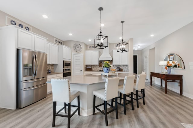 kitchen with tasteful backsplash, a center island, appliances with stainless steel finishes, pendant lighting, and white cabinets