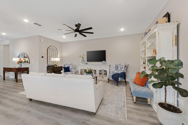 living room with light hardwood / wood-style flooring and ceiling fan