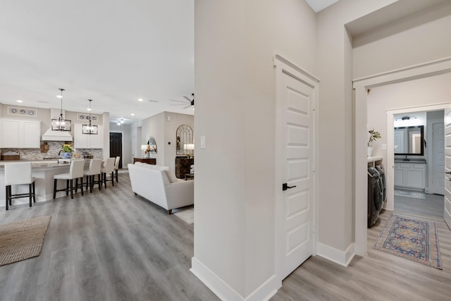 hallway with an inviting chandelier and light hardwood / wood-style flooring