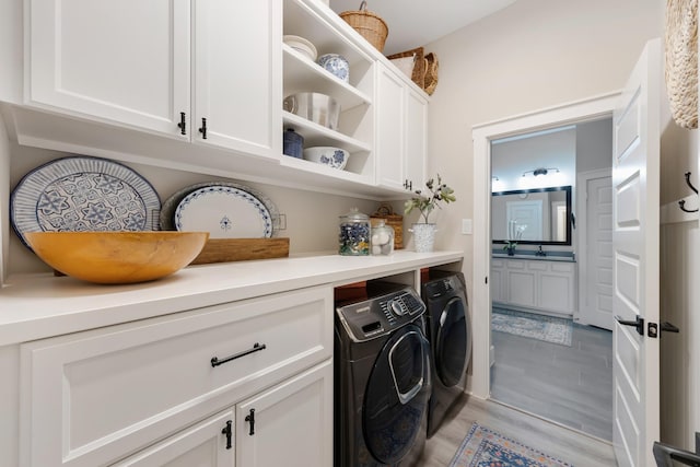 washroom with cabinets, washing machine and clothes dryer, and light hardwood / wood-style floors