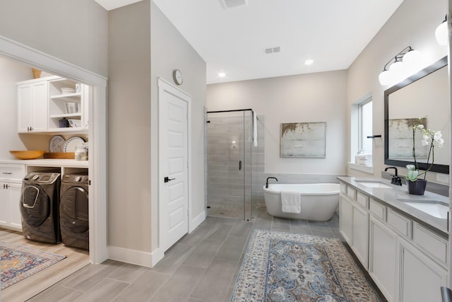 bathroom with plus walk in shower, vanity, and washer and clothes dryer