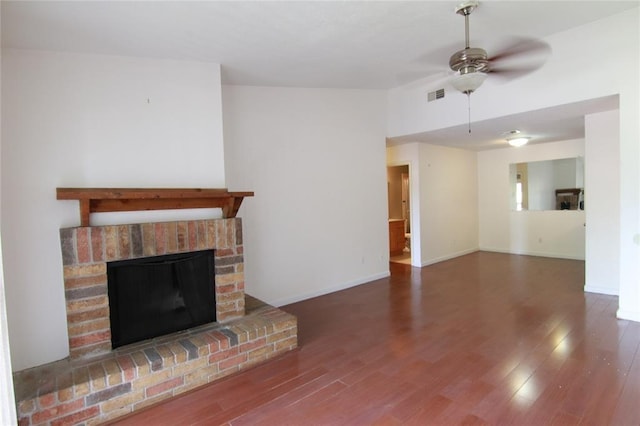 unfurnished living room featuring dark hardwood / wood-style flooring, a brick fireplace, and ceiling fan