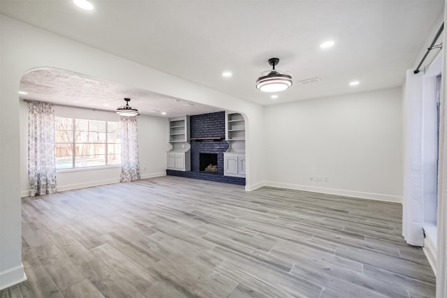 unfurnished living room featuring ceiling fan, a fireplace, and light hardwood / wood-style floors