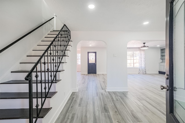 entrance foyer featuring arched walkways, recessed lighting, wood finished floors, baseboards, and stairway