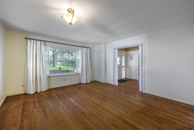 spare room featuring dark wood-style floors and baseboards