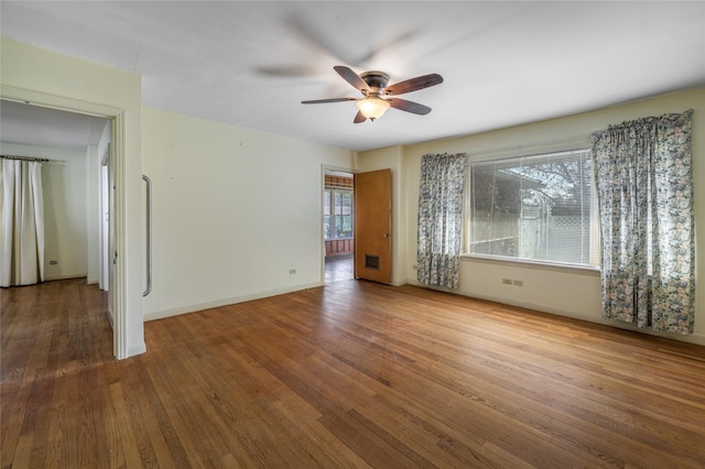 empty room with a ceiling fan, baseboards, and wood finished floors