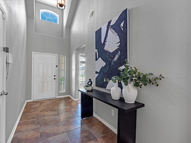 entrance foyer featuring a towering ceiling and dark tile patterned floors