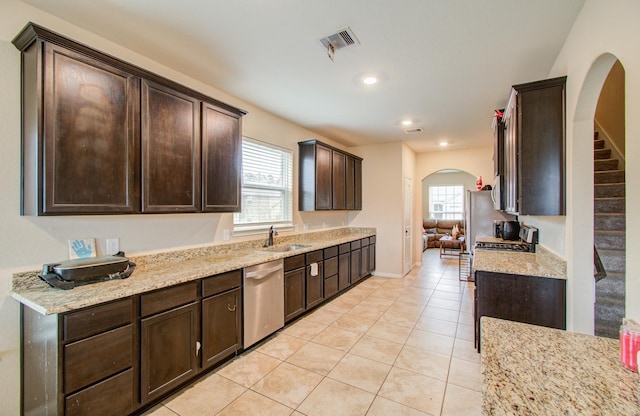 kitchen featuring light tile patterned flooring, dishwasher, sink, dark brown cabinetry, and light stone countertops