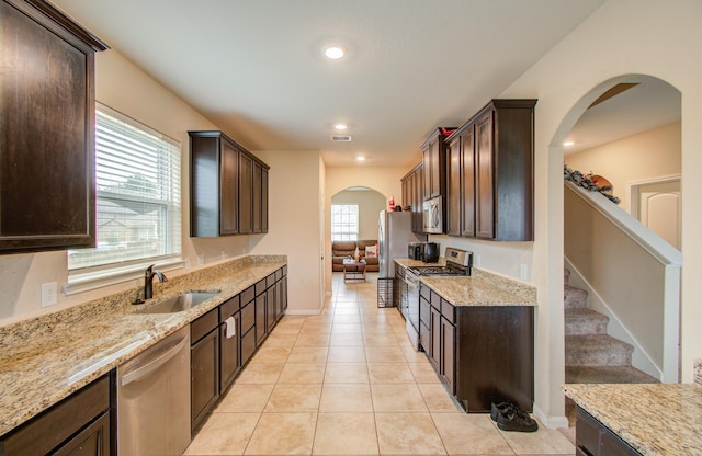 kitchen with stainless steel appliances, light stone countertops, sink, and light tile patterned floors