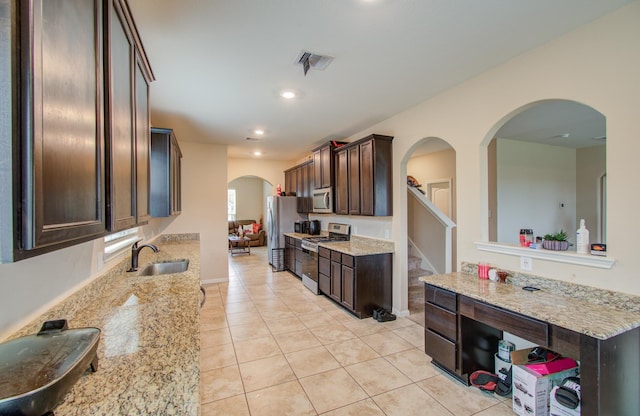 kitchen featuring sink, light tile patterned flooring, stainless steel appliances, and light stone countertops