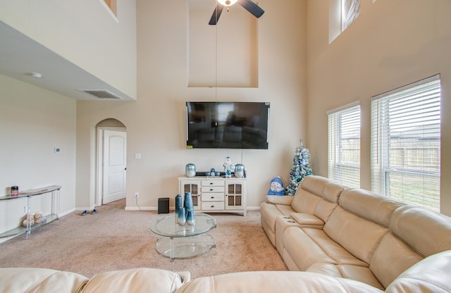 living room featuring light carpet, ceiling fan, and a high ceiling