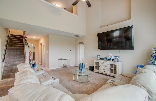 living room featuring ceiling fan, carpet flooring, and a towering ceiling