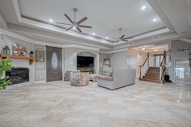 unfurnished living room with ceiling fan, ornamental molding, a fireplace, and a raised ceiling