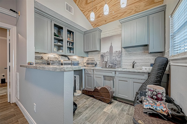 kitchen featuring gray cabinets, lofted ceiling, backsplash, and decorative light fixtures