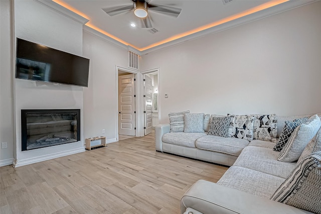 living room with crown molding, ceiling fan, and light wood-type flooring