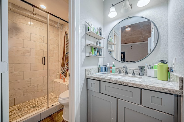 bathroom featuring hardwood / wood-style flooring, vanity, toilet, and a shower with door