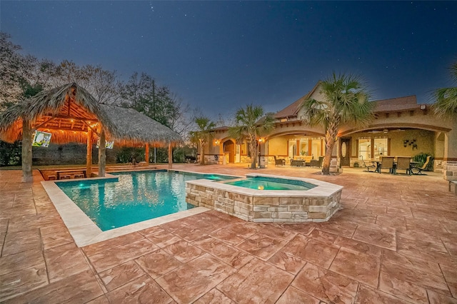 pool at twilight featuring a gazebo, an in ground hot tub, and a patio area