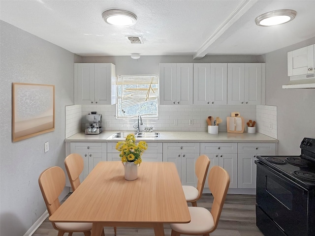 kitchen featuring tasteful backsplash, black / electric stove, sink, and white cabinets