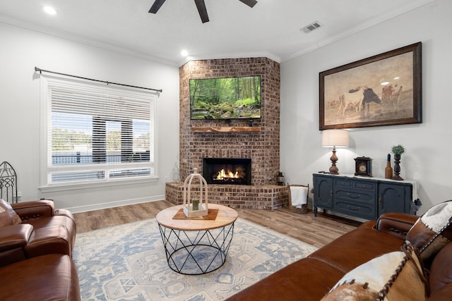 living room with crown molding, ceiling fan, a fireplace, and light hardwood / wood-style floors