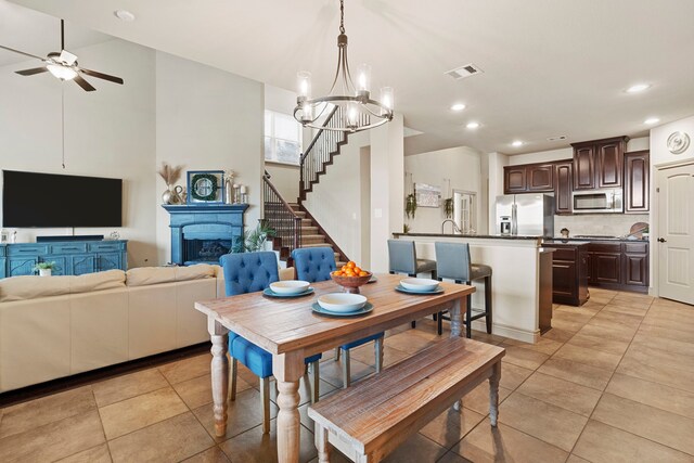 dining space featuring light tile patterned floors, ceiling fan with notable chandelier, and sink