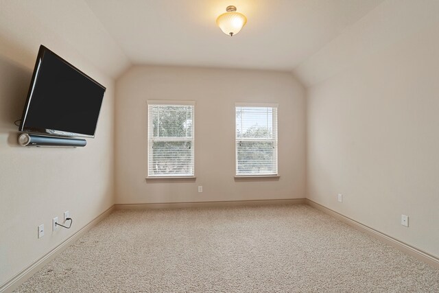 carpeted spare room with lofted ceiling