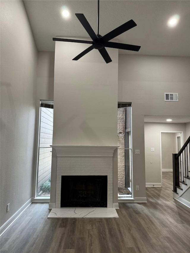 unfurnished living room with a brick fireplace, wood-type flooring, and ceiling fan