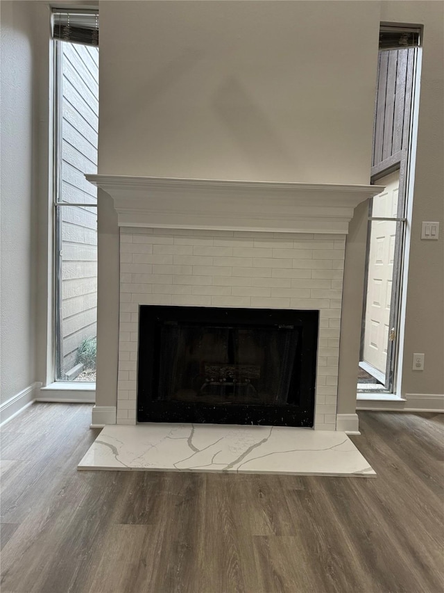 interior details with wood-type flooring and a brick fireplace