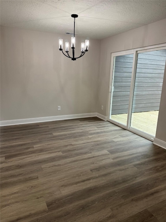 unfurnished room with a notable chandelier, dark hardwood / wood-style floors, and a textured ceiling