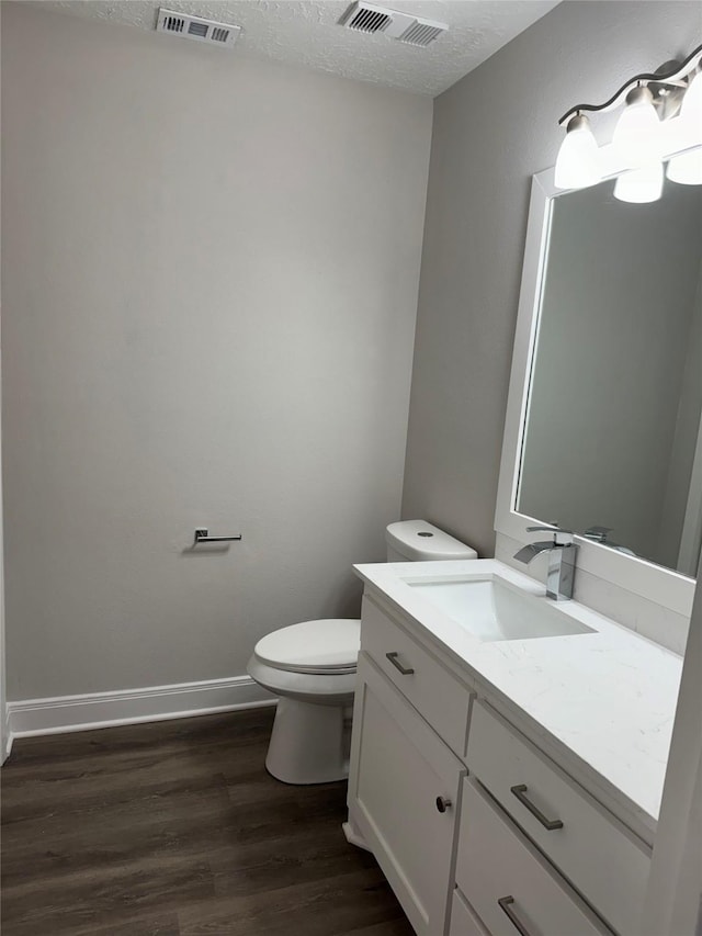 bathroom with hardwood / wood-style flooring, vanity, a textured ceiling, and toilet